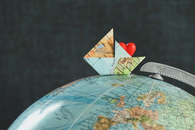 Papierschiff fährt über Globus, darin ein rotes Herz-Expat Coaching bereitet gut auf Auslandsentsendungen vor