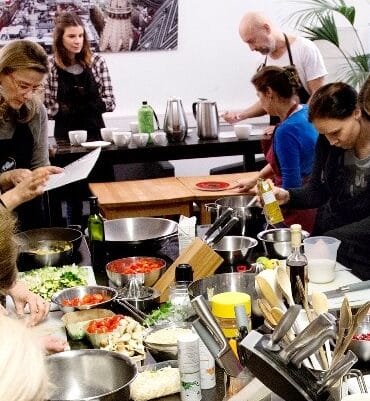 Teammitglieder eines Unternehmens die beim Teamevent "Kochen & Coaching" kochen und dabei lernen und die Kommunikation verbessern